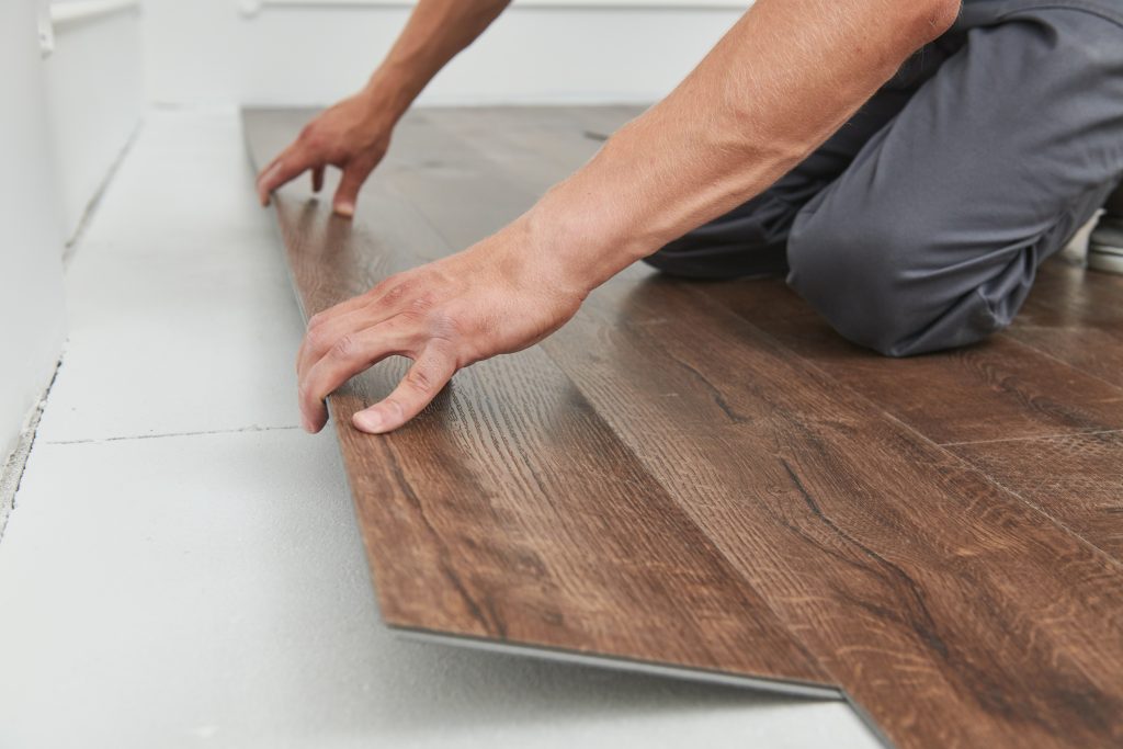 Professional installer fitting engineered wood flooring in a herringbone pattern during a precision flooring installation.